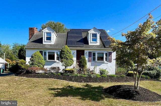 cape cod home featuring a front lawn and solar panels