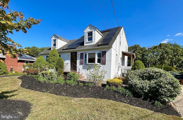 new england style home featuring a front lawn and solar panels