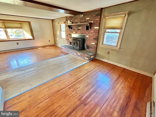 unfurnished living room featuring hardwood / wood-style floors, plenty of natural light, beam ceiling, and baseboard heating