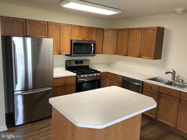 kitchen featuring a center island, dark hardwood / wood-style flooring, stainless steel appliances, and sink