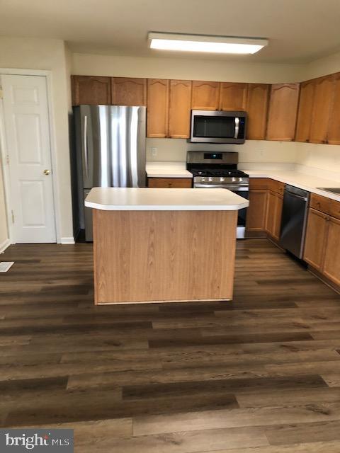 kitchen with a center island, dark wood-type flooring, and appliances with stainless steel finishes