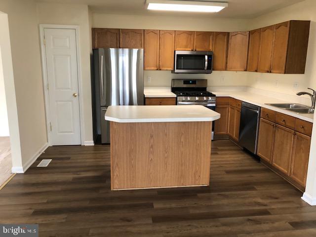 kitchen with sink, a kitchen island, dark hardwood / wood-style flooring, and stainless steel appliances