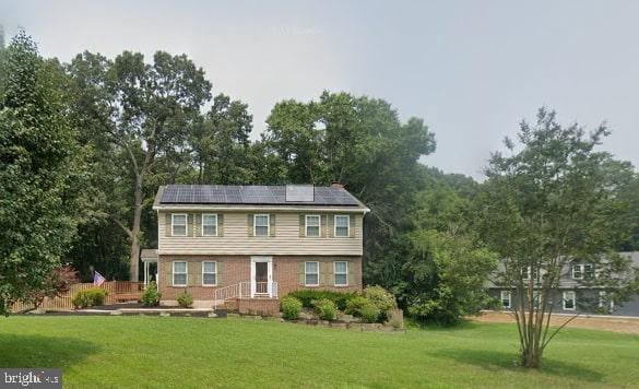 view of front of property with a front yard and solar panels