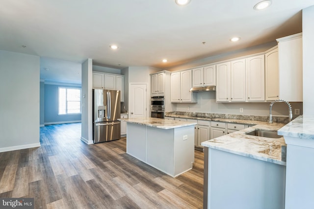 kitchen featuring a center island, sink, appliances with stainless steel finishes, dark hardwood / wood-style flooring, and white cabinetry