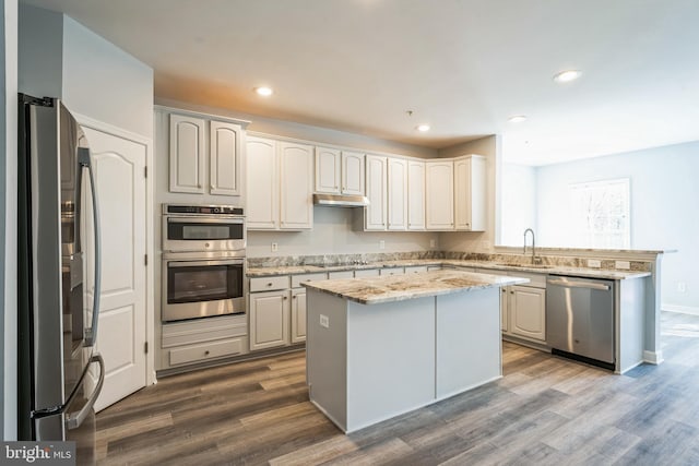 kitchen with hardwood / wood-style floors, a kitchen island, sink, and stainless steel appliances