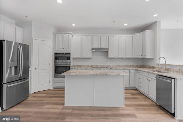 kitchen featuring white cabinetry, sink, appliances with stainless steel finishes, a kitchen island, and light wood-type flooring