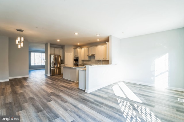 kitchen featuring kitchen peninsula, hardwood / wood-style floors, stainless steel appliances, and pendant lighting