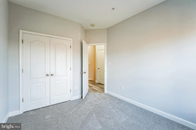 unfurnished bedroom featuring a closet and light colored carpet