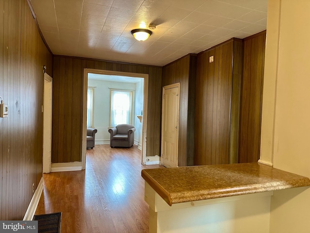 hallway with light hardwood / wood-style floors and wood walls