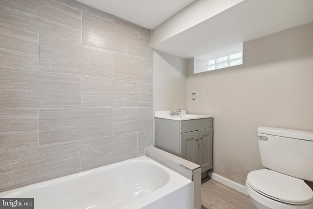 bathroom with hardwood / wood-style floors, vanity, toilet, and a tub