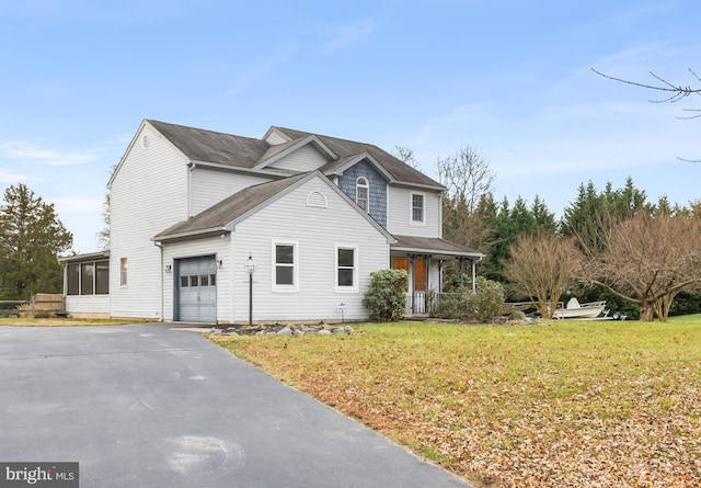 view of front property with covered porch, a garage, and a front yard