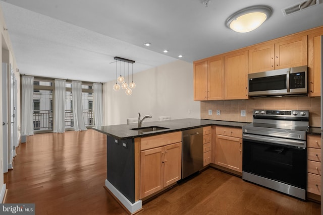 kitchen featuring kitchen peninsula, stainless steel appliances, tasteful backsplash, decorative light fixtures, and sink