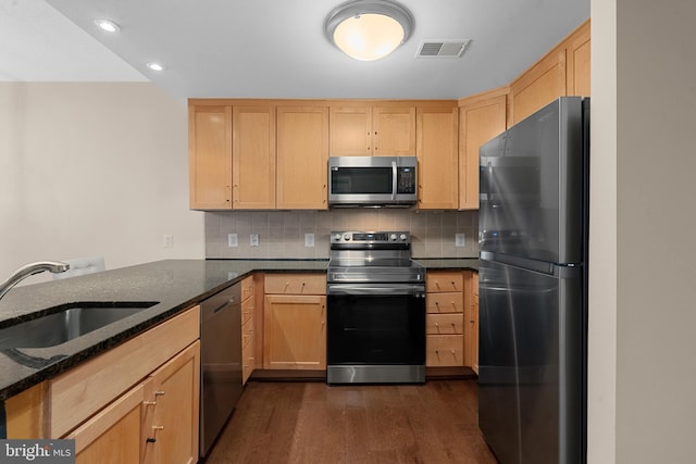 kitchen with decorative backsplash, sink, dark stone counters, appliances with stainless steel finishes, and dark hardwood / wood-style flooring