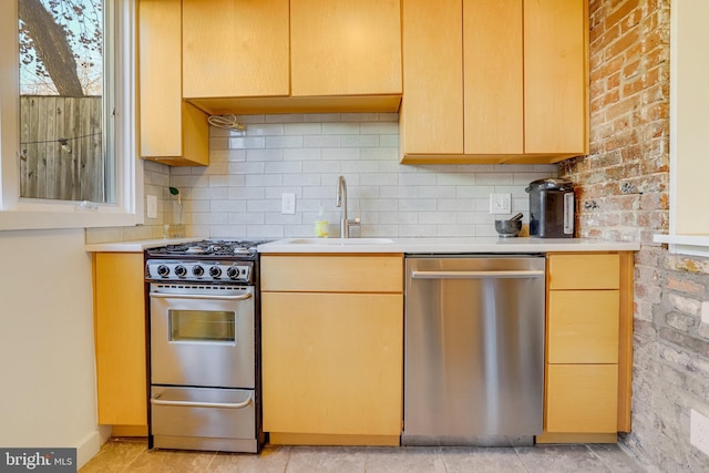 kitchen featuring light brown cabinetry, tasteful backsplash, brick wall, stainless steel appliances, and sink