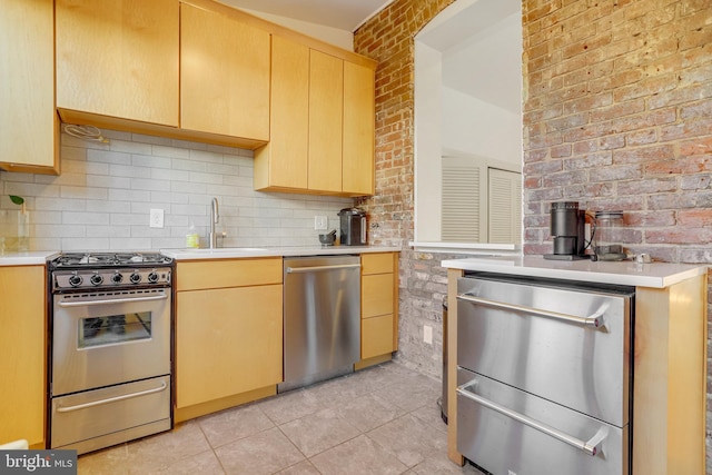 kitchen featuring decorative backsplash, light tile patterned floors, stainless steel appliances, and brick wall