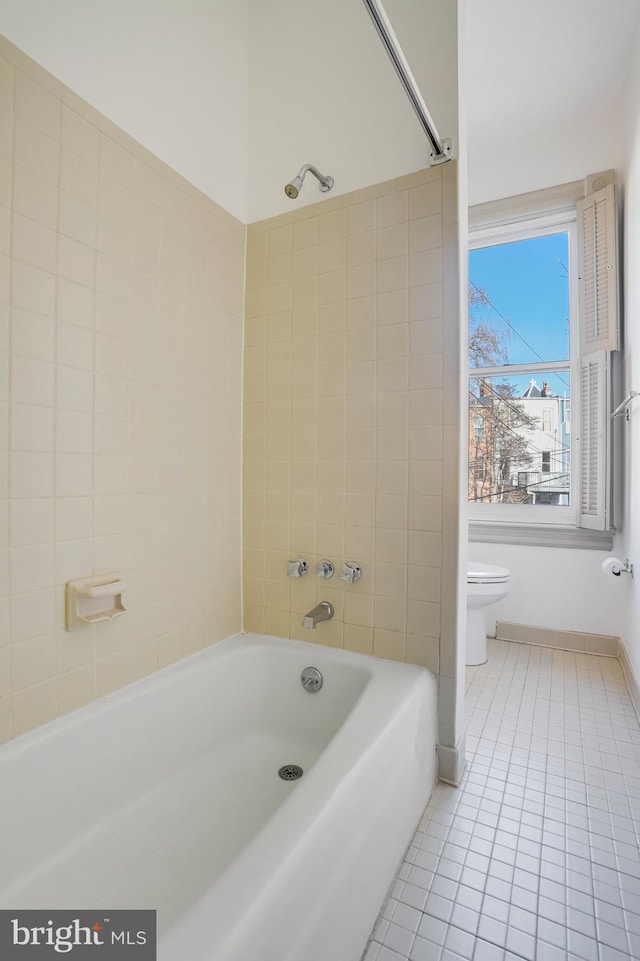 bathroom featuring toilet, tiled shower / bath combo, and tile patterned floors