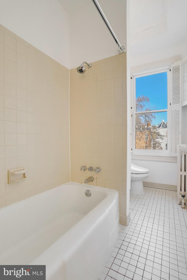 bathroom with tile patterned flooring, toilet, and tiled shower / bath