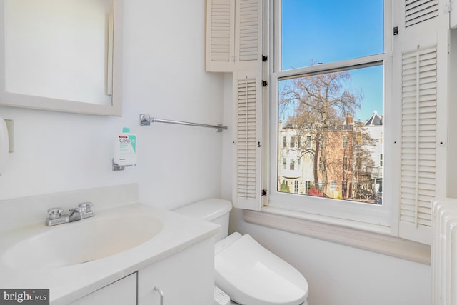 bathroom featuring radiator heating unit, vanity, and toilet