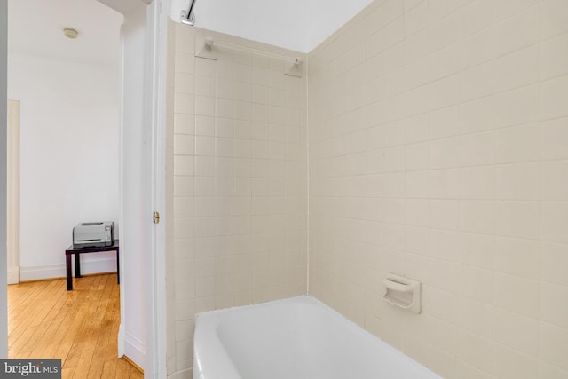 bathroom featuring wood-type flooring and tiled shower / bath