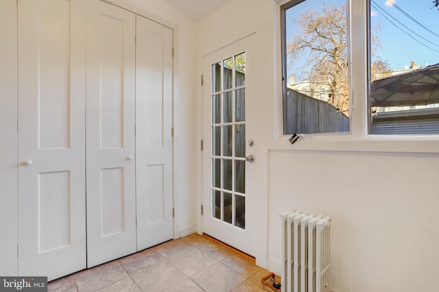 doorway featuring light tile patterned flooring and radiator heating unit