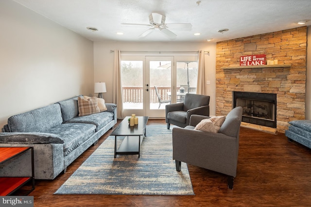 living room featuring a fireplace, ceiling fan, dark hardwood / wood-style flooring, and a textured ceiling