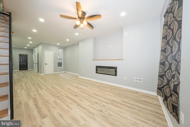 unfurnished living room featuring heating unit, ceiling fan, and light hardwood / wood-style floors