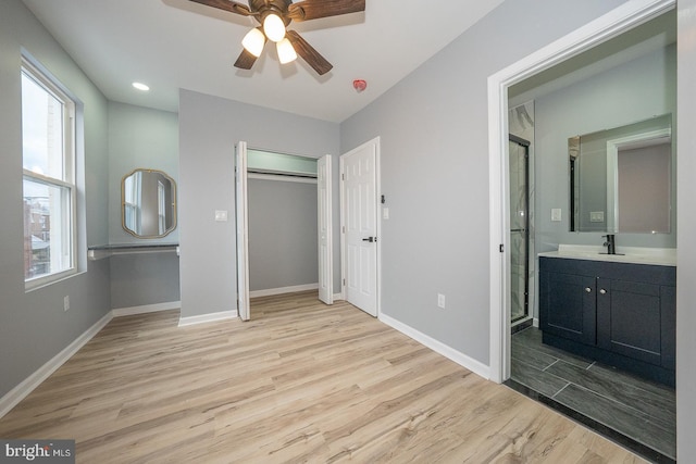 unfurnished bedroom with ceiling fan, light hardwood / wood-style floors, sink, and ensuite bathroom