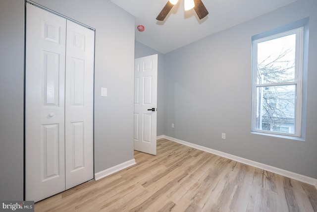 unfurnished bedroom with ceiling fan, a closet, lofted ceiling, and light hardwood / wood-style flooring