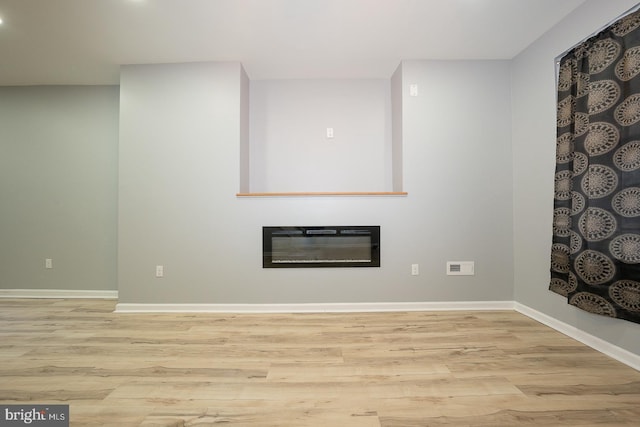 unfurnished living room with heating unit and light hardwood / wood-style flooring