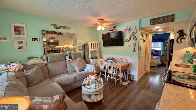 living room with a textured ceiling, dark hardwood / wood-style flooring, ceiling fan, and sink