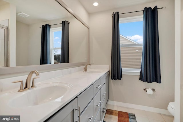 bathroom with toilet, vanity, and tile patterned floors