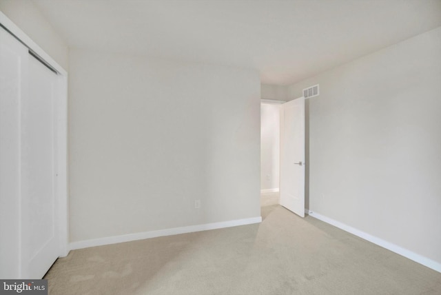 unfurnished bedroom with light colored carpet and a closet