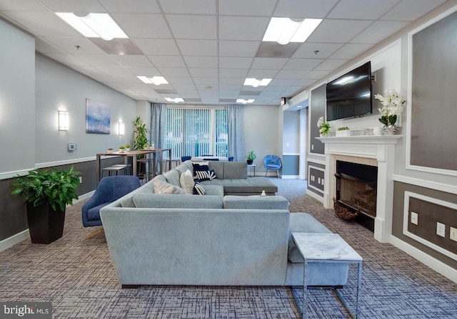 living room with a drop ceiling and carpet