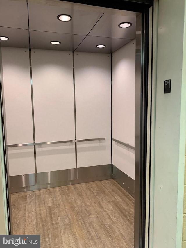 interior details featuring hardwood / wood-style flooring, a drop ceiling, and elevator