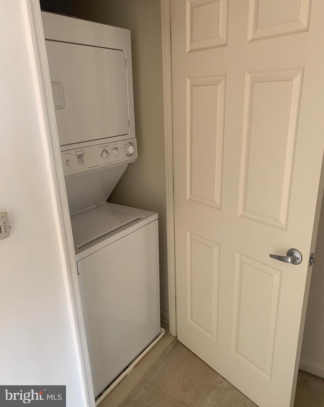 laundry area featuring light colored carpet and stacked washer and clothes dryer