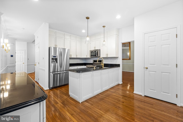 kitchen featuring pendant lighting, dark wood-type flooring, appliances with stainless steel finishes, tasteful backsplash, and white cabinetry