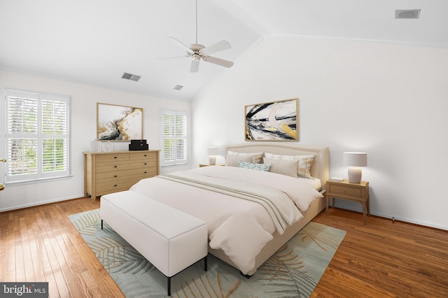 bedroom featuring wood-type flooring, high vaulted ceiling, multiple windows, and ceiling fan