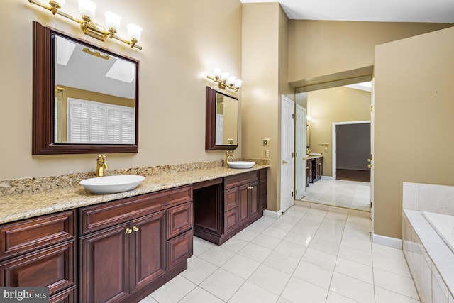 bathroom with tile patterned flooring, vanity, tiled bath, and vaulted ceiling