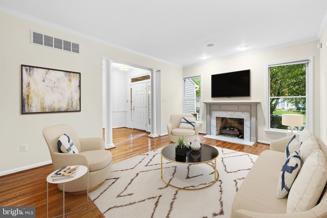 living room with a healthy amount of sunlight, crown molding, a high end fireplace, and wood-type flooring