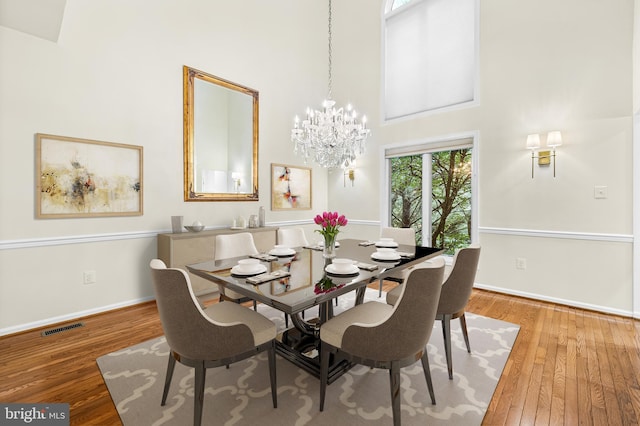 dining room with a towering ceiling, hardwood / wood-style flooring, and a notable chandelier