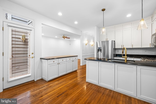 kitchen featuring decorative light fixtures, dark hardwood / wood-style flooring, white cabinetry, and stainless steel appliances