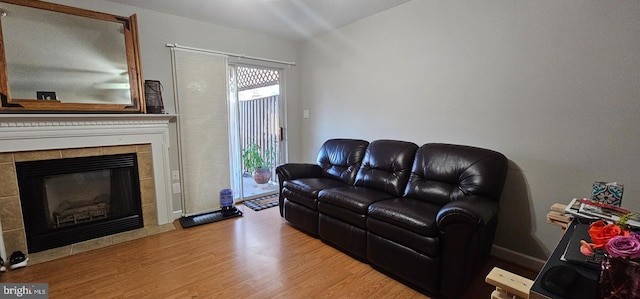 living room with light wood-type flooring and a tiled fireplace