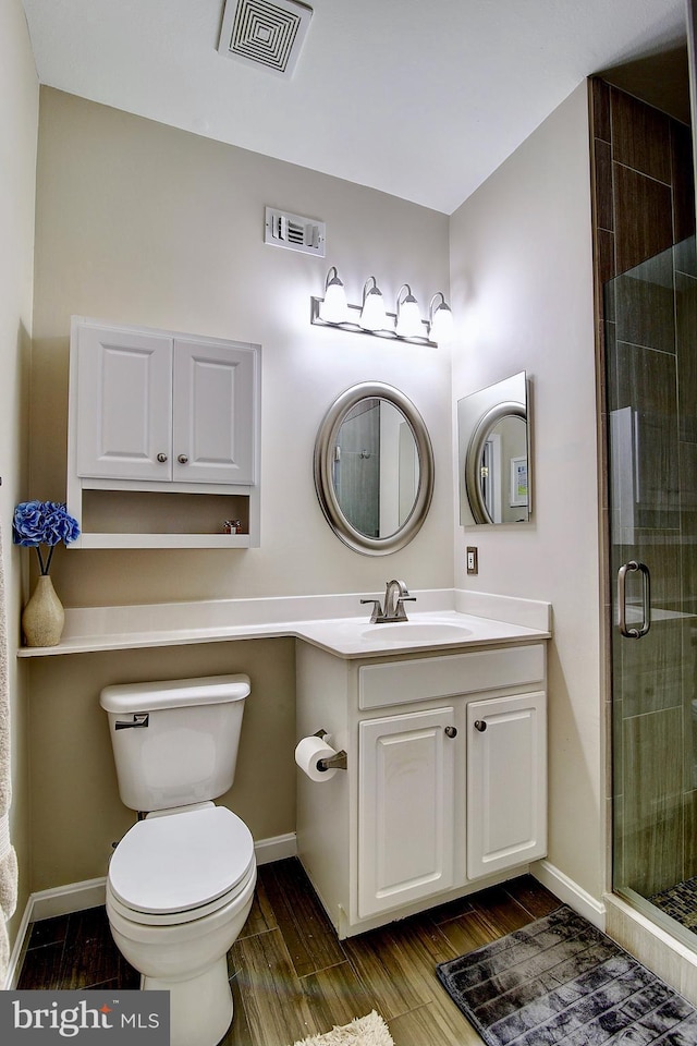 bathroom with hardwood / wood-style floors, vanity, toilet, and a shower with door