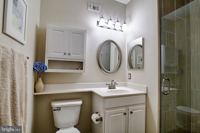 bathroom with vanity, a shower with shower door, and toilet