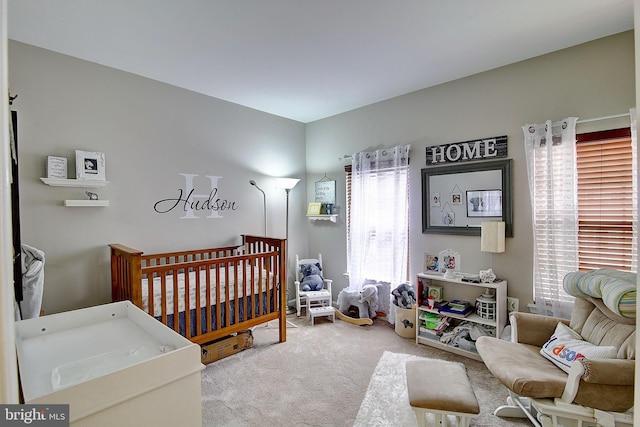 carpeted bedroom featuring a nursery area