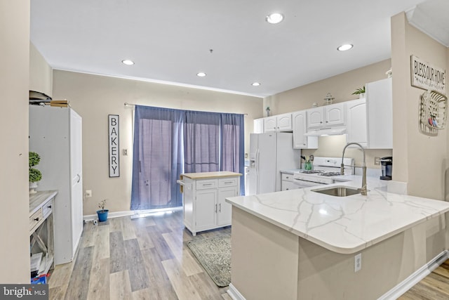 kitchen featuring white appliances, white cabinets, light stone countertops, light wood-type flooring, and kitchen peninsula