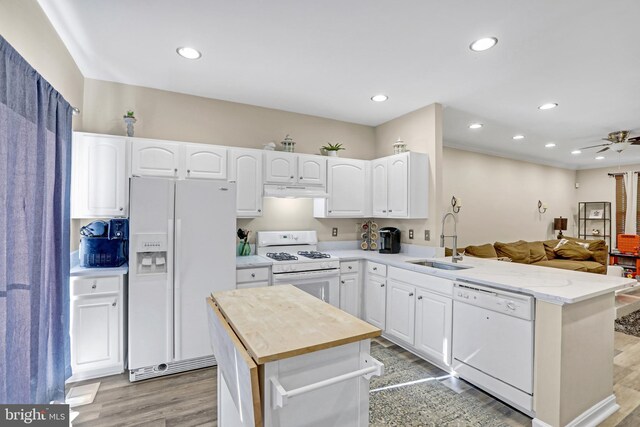 kitchen featuring white cabinets, kitchen peninsula, white appliances, and sink