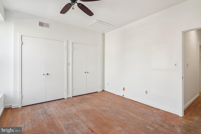 unfurnished bedroom featuring ceiling fan, two closets, and light wood-type flooring