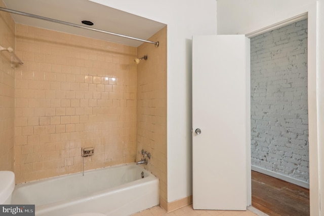 bathroom with toilet and tiled shower / bath