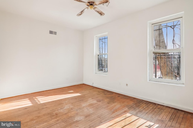 spare room with light wood-type flooring, ceiling fan, and a healthy amount of sunlight